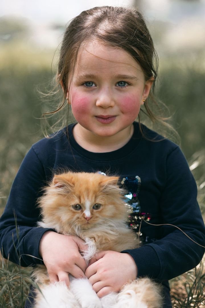 Young girl holding a fluffy cream kitten